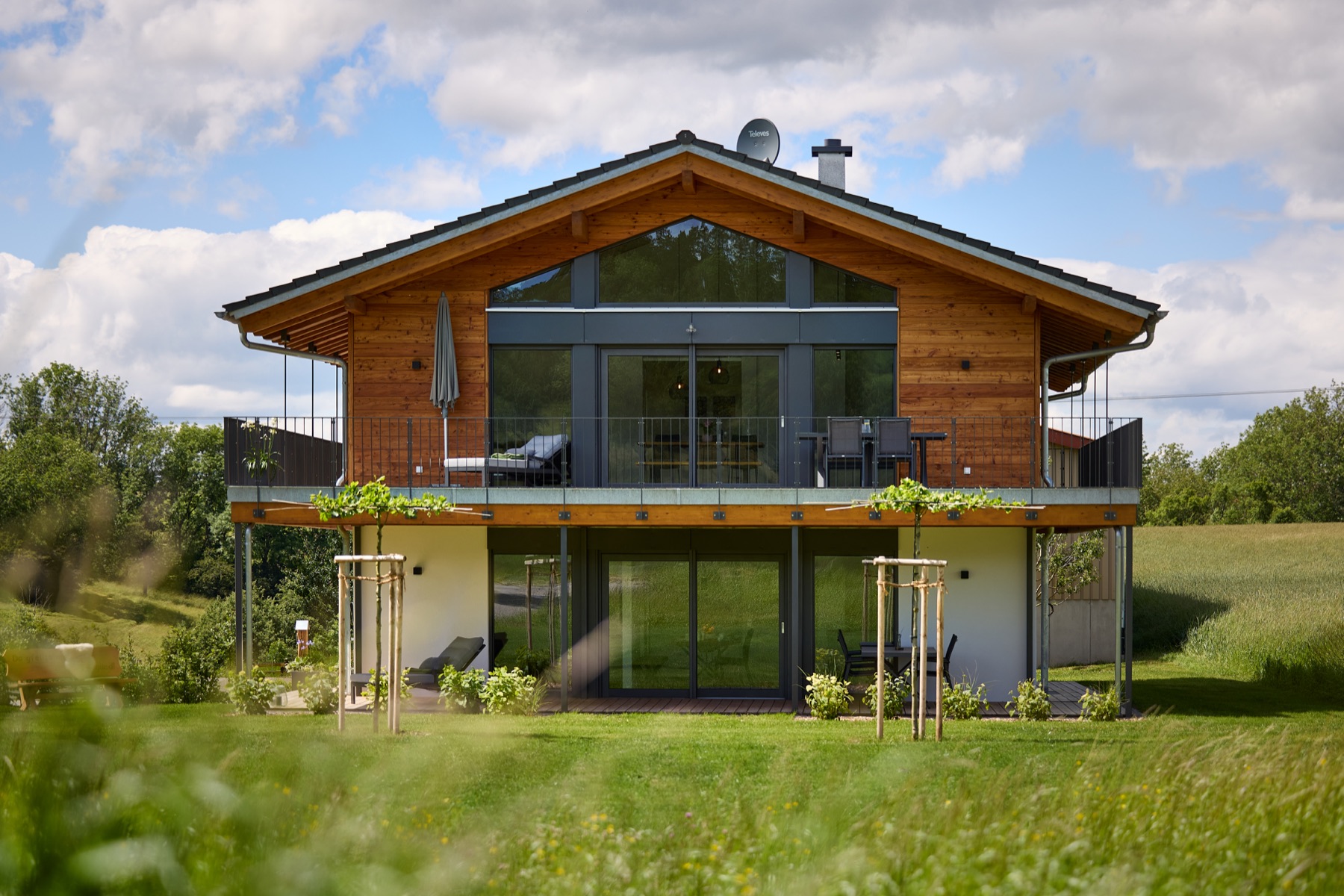 Architekturfotografie eines modernen Holzhauses in einer grünen Wiesenlandschaft